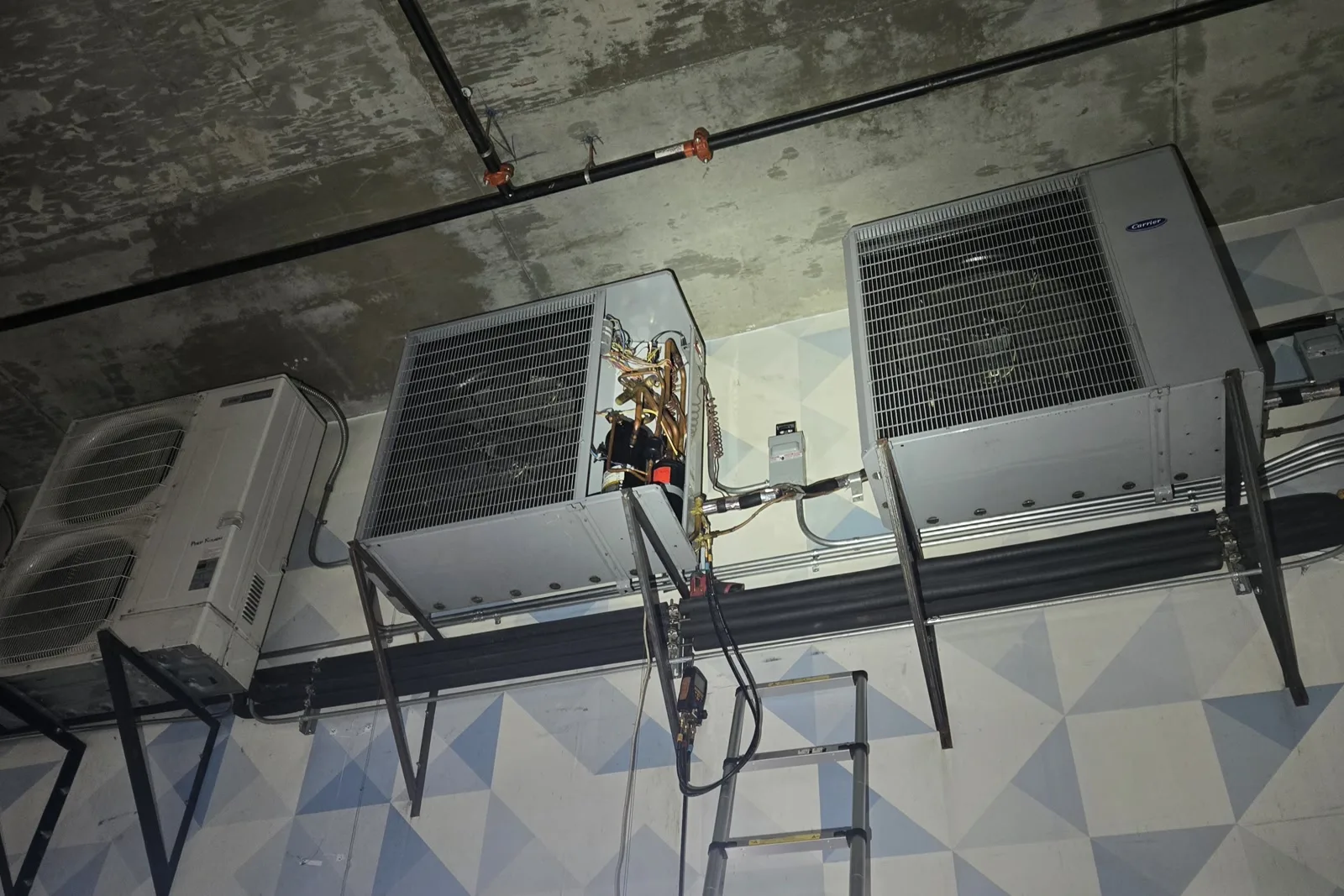 Three HVAC condenser units mounted near the ceiling of an underground garage at a Downtown Los Angeles restaurant