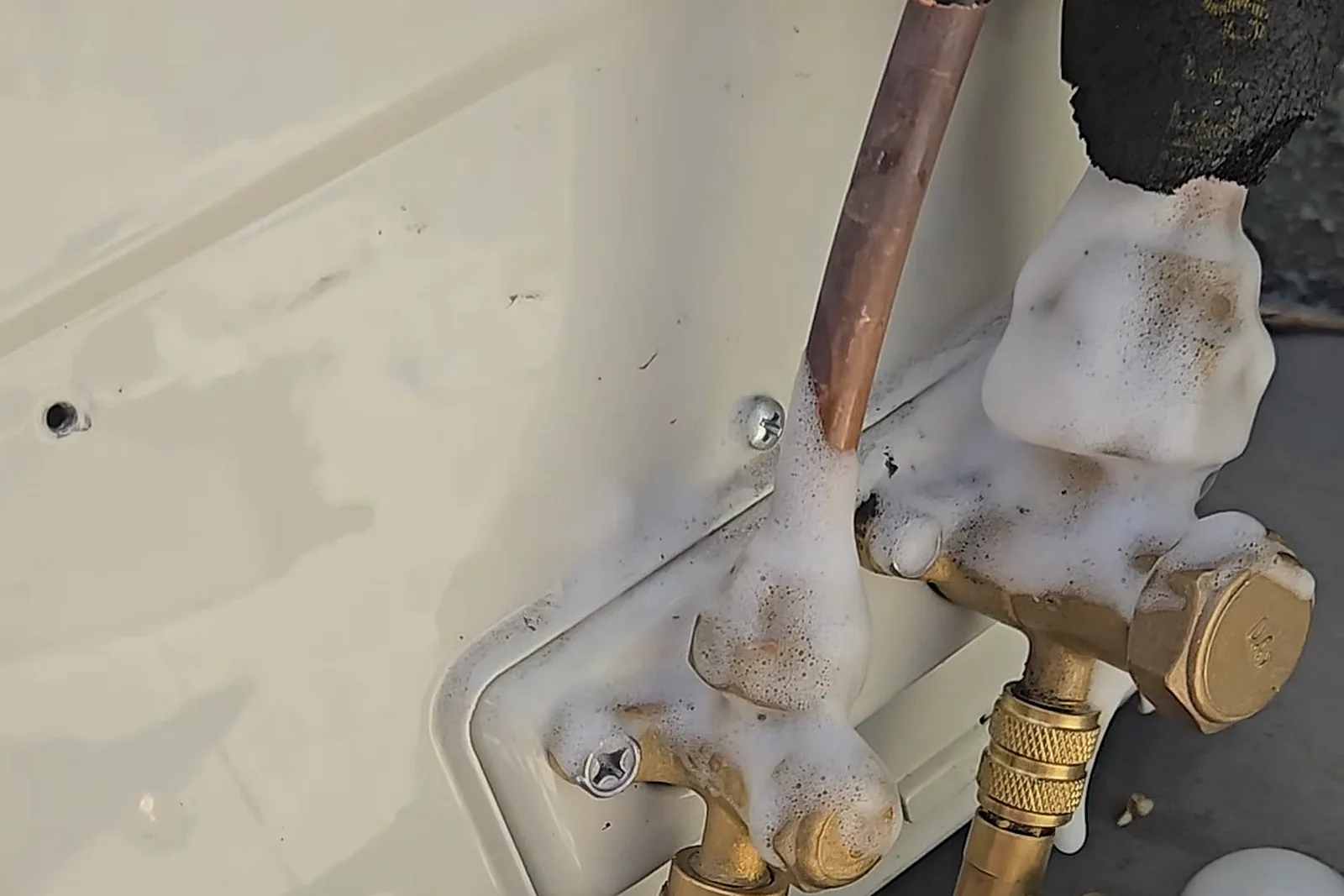 Thick foam from a bubble test on the repaired flare fittings of the HVAC system