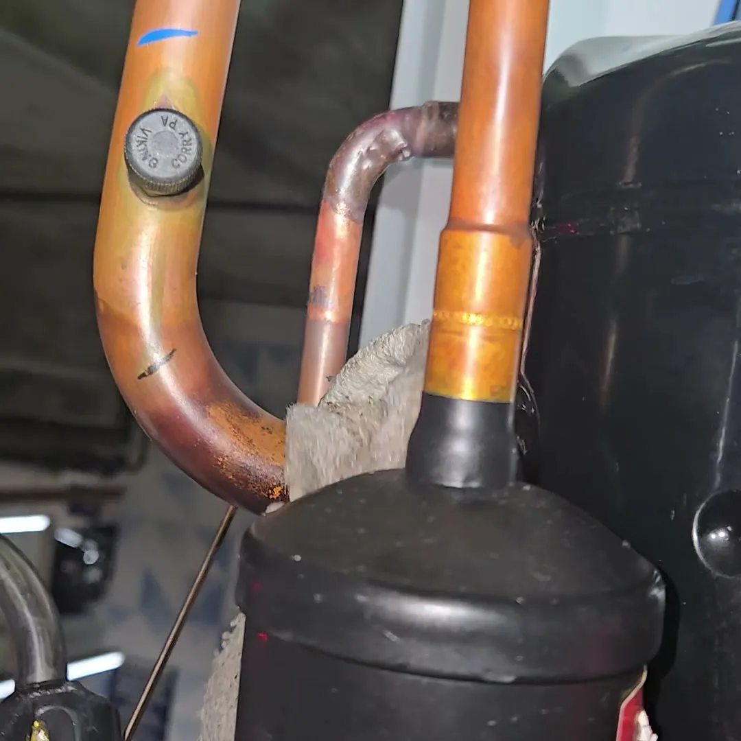 Oily residue caked at the bottom of the copper bend where the refrigerant was escaping