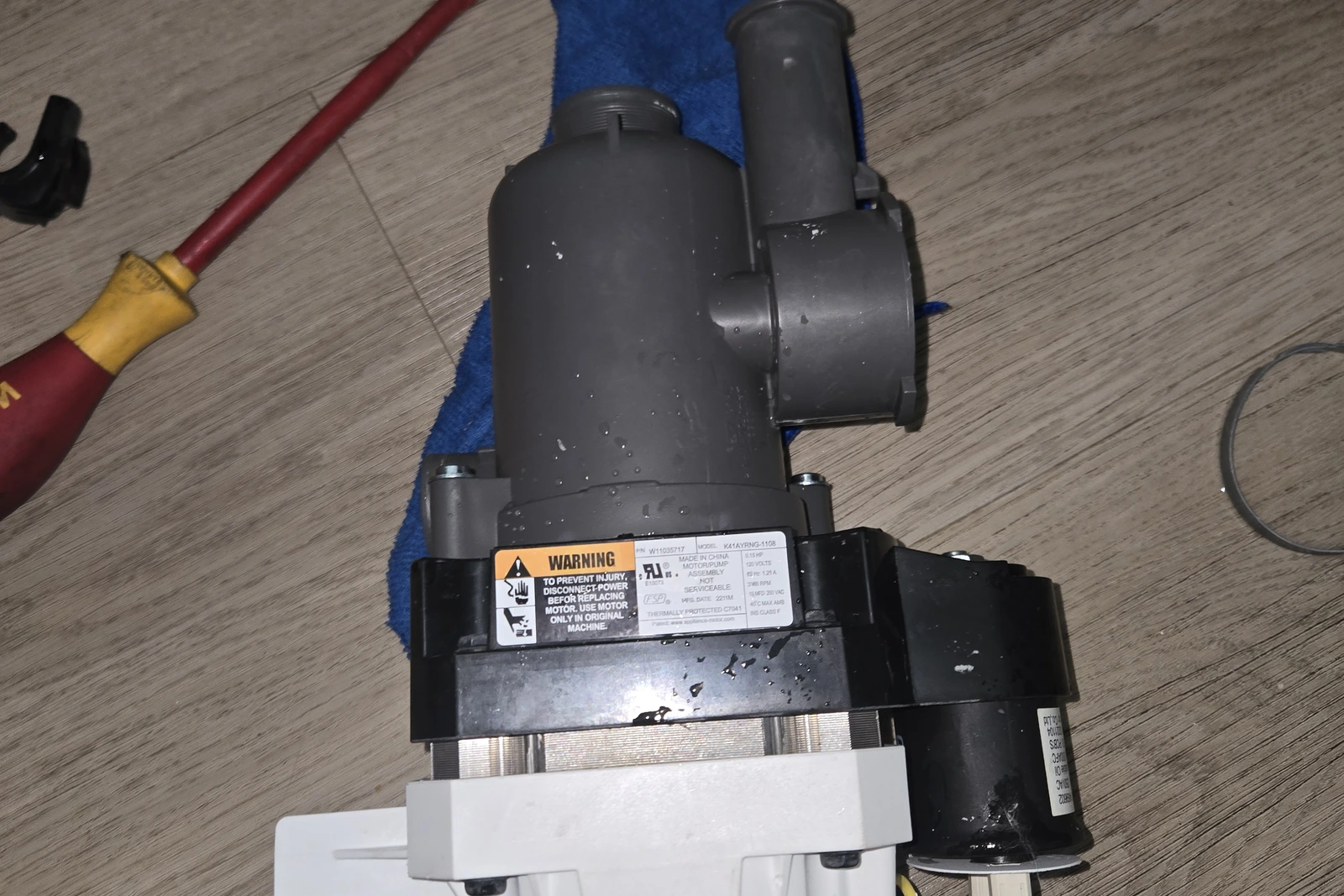 KitchenAid dishwasher circulation pump and motor after being hosed out and cleaned, resting on the floor