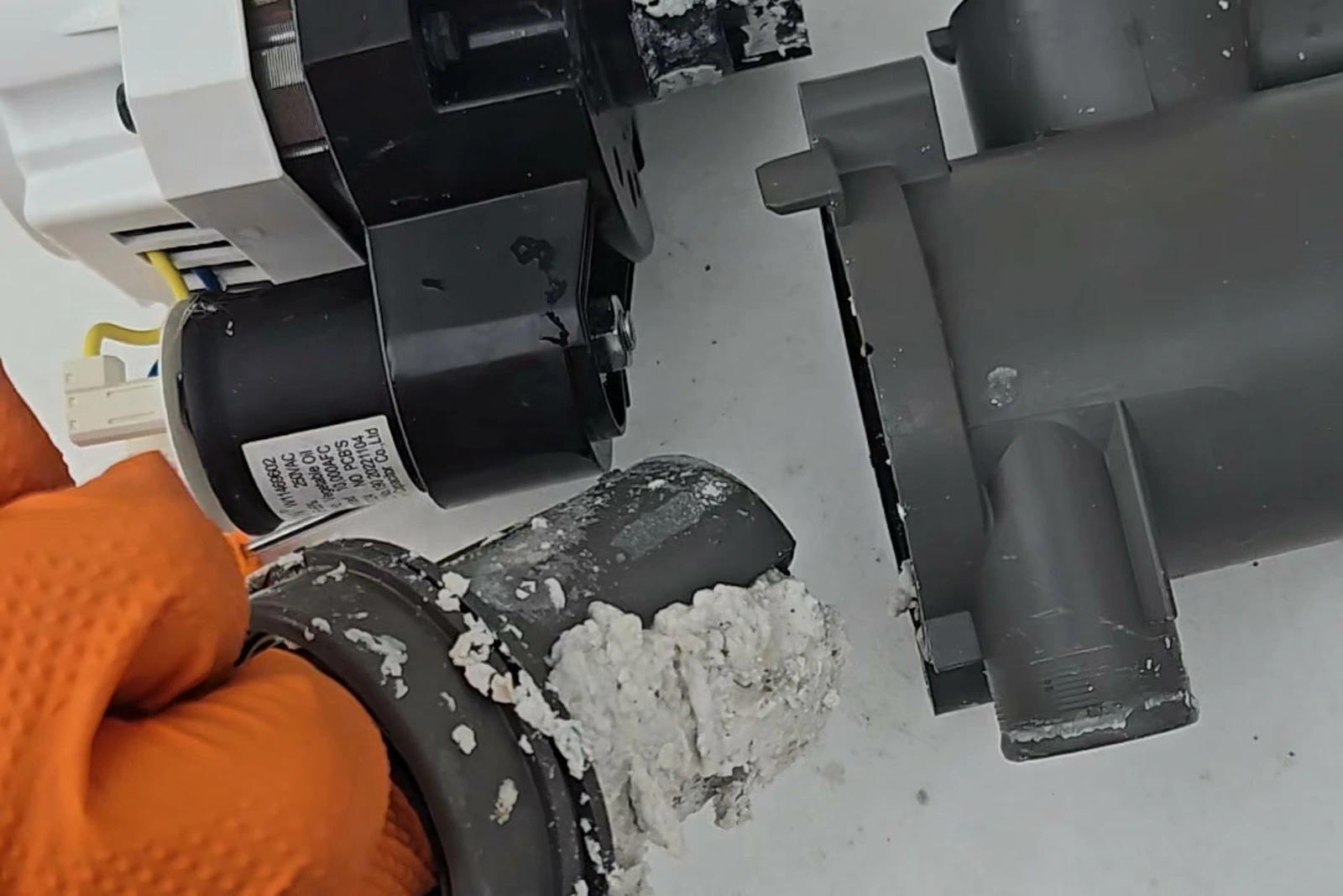 Undissolved detergent powder packed inside the circulation pump housing of a KitchenAid dishwasher