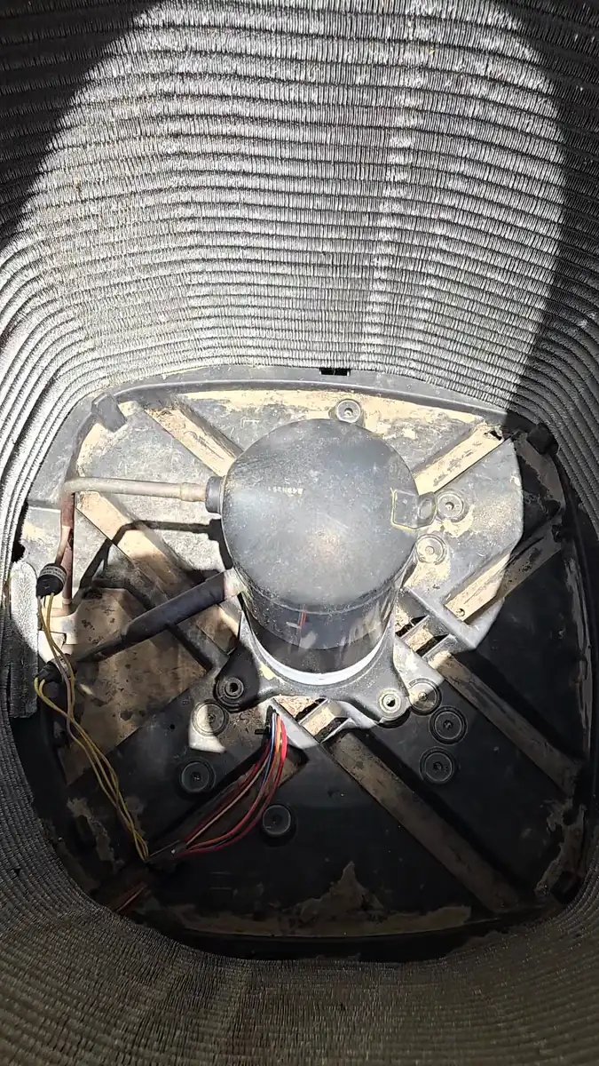 Vista desde arriba hacia el serpentín del condensador, con el compresor asentado en la base de la unidad y sus líneas de cobre y su cableado conectados