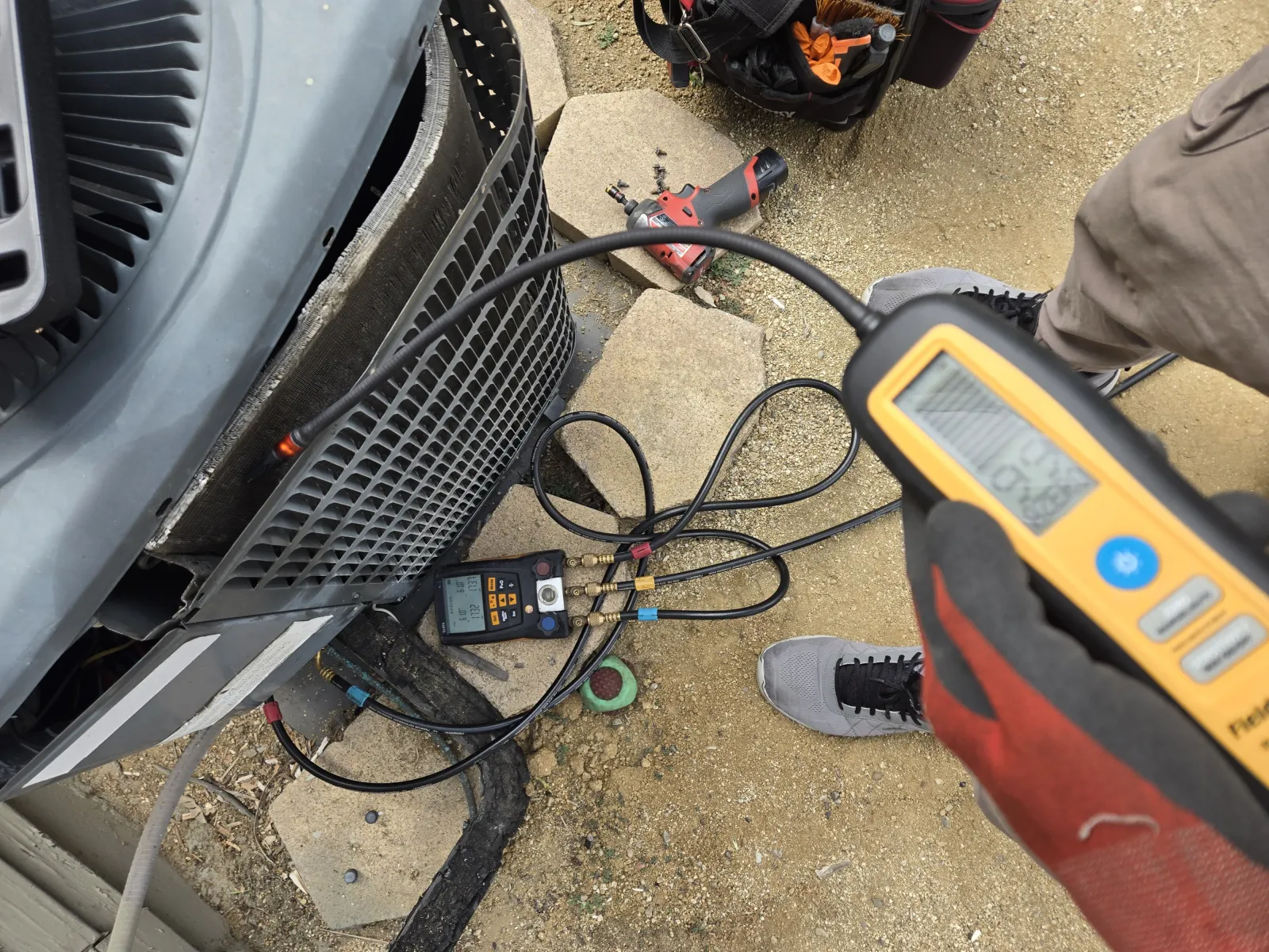 Manómetros digitales y un detector de fugas electrónico en un viejo condensador de R22 durante una búsqueda de fuga de refrigerante en Sherman Oaks.