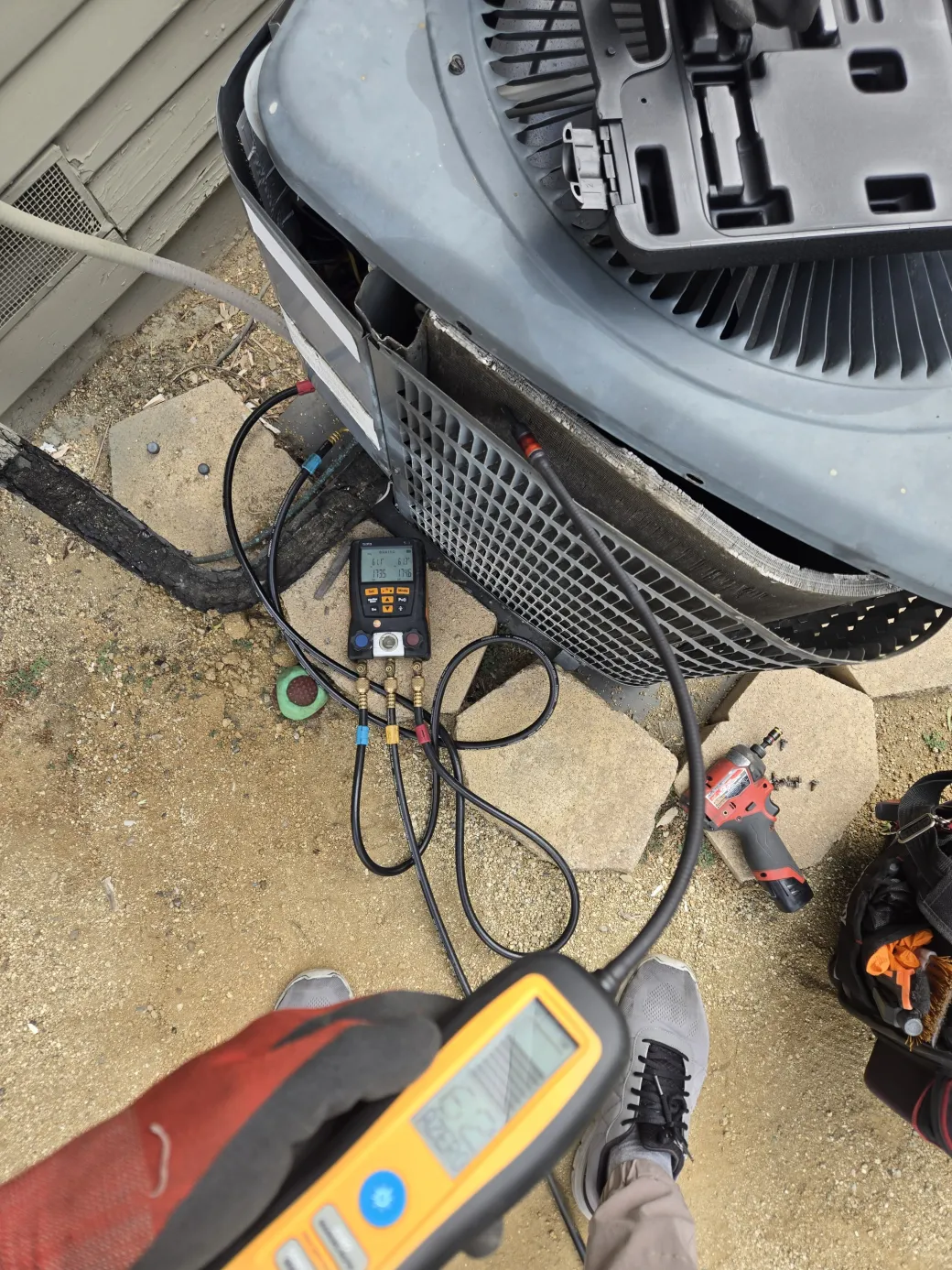 Un detector de fugas electrónico y manómetros conectados al condensador de R22 para ubicar la fuga de refrigerante en Sherman Oaks.