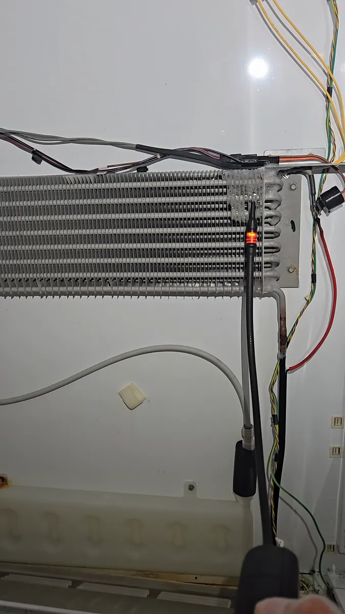 Detector electrónico de fugas revisando el serpentín del evaporador de un refrigerador empotrado