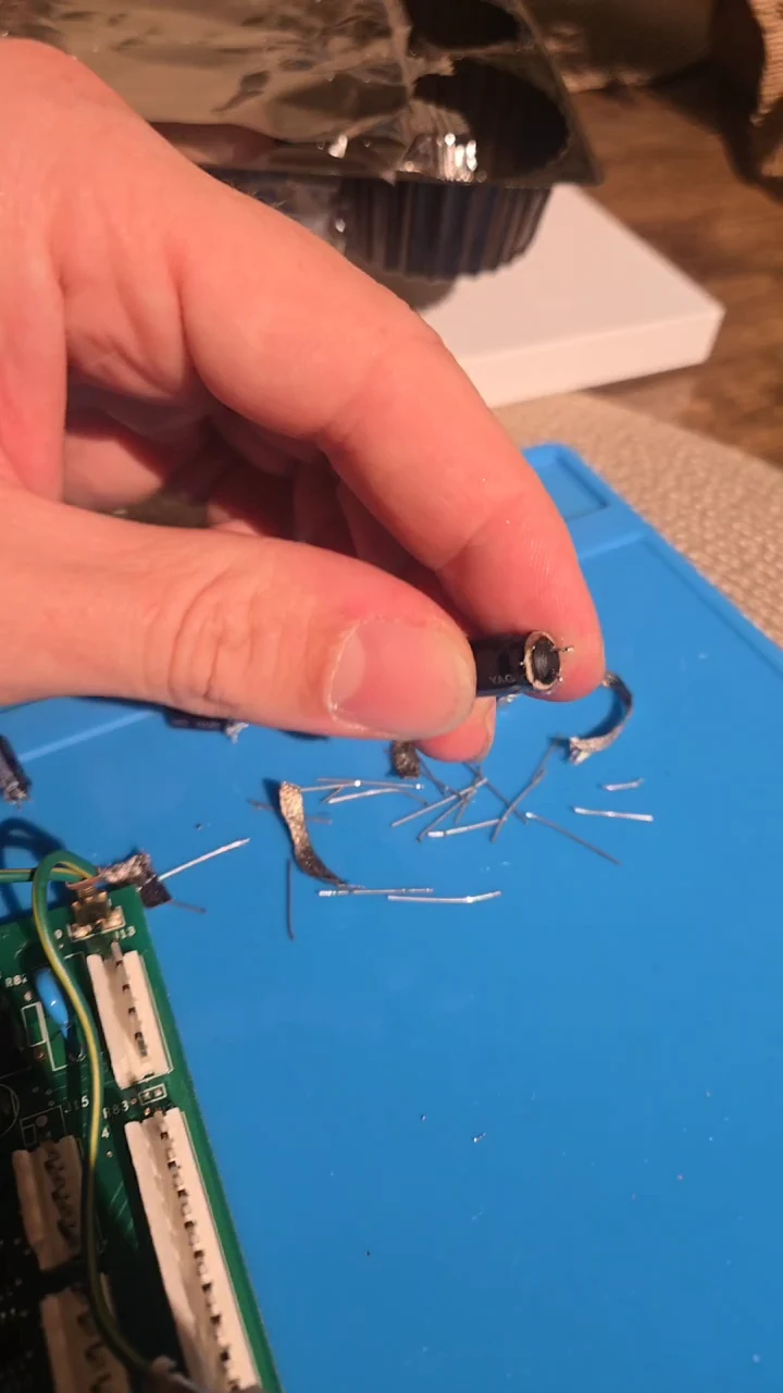 A removed capacitor viewed from underneath, showing damage around its bottom seal.