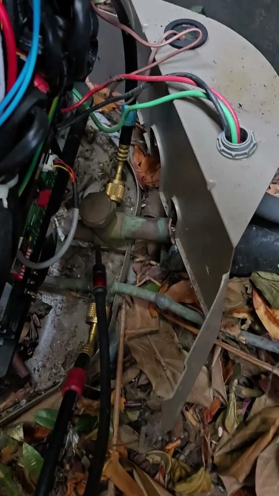 Service valves at the base of the heat pump with gauge hoses connected, where the nitrogen test found the leak at the suction valve