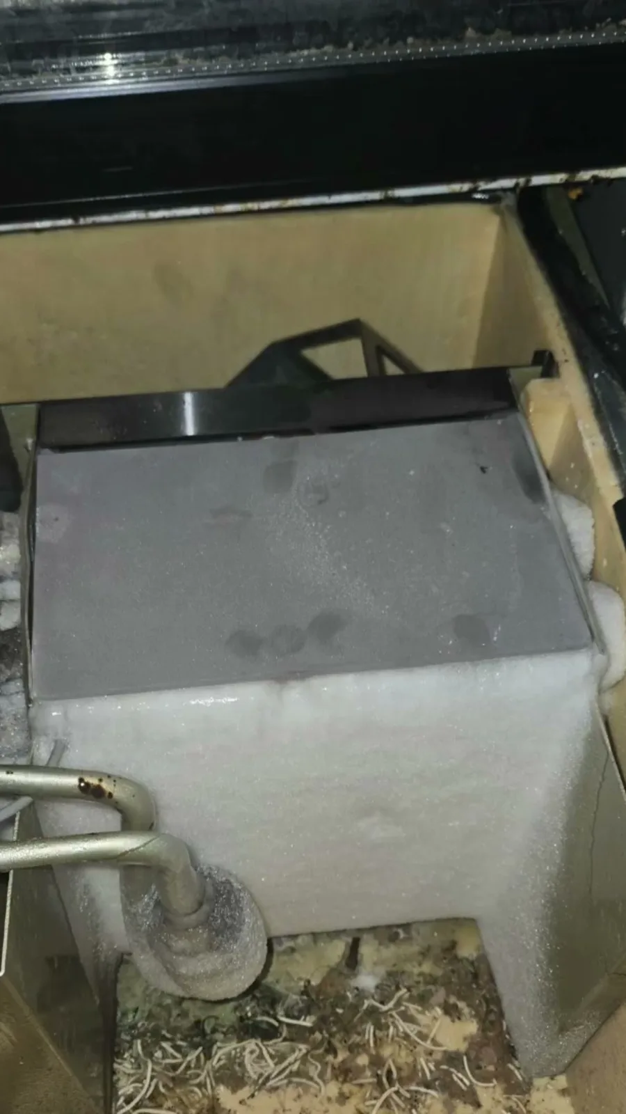 Evaporator housing in the bottom compartment of the glass-door cooler, encased in a solid block of ice
