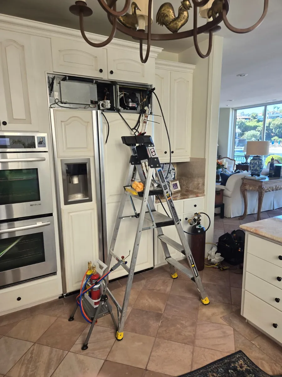 Técnico de Epic Star reparando el compresor superior de un refrigerador empotrado en una cocina de Beverly Hills