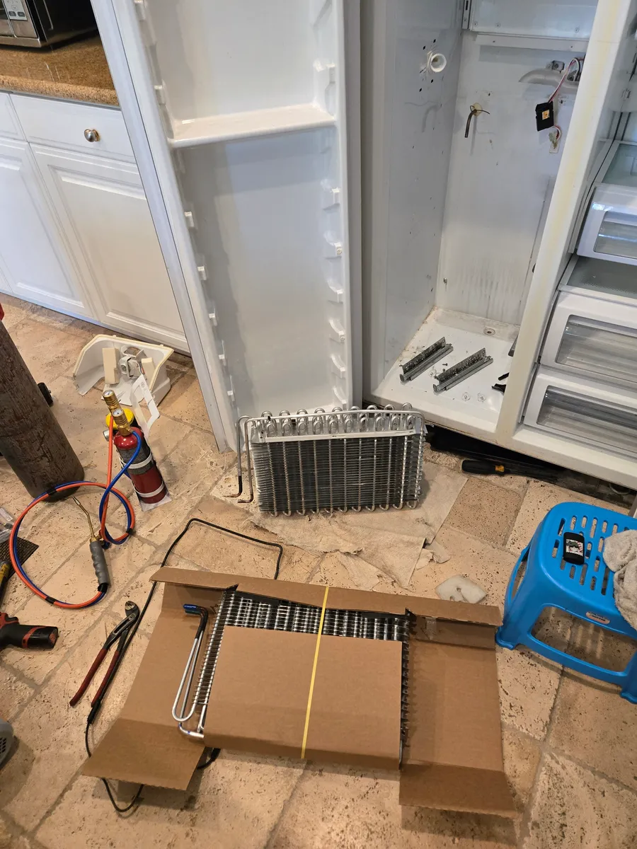 Evaporator coil beside an opened built-in KitchenAid refrigerator during service