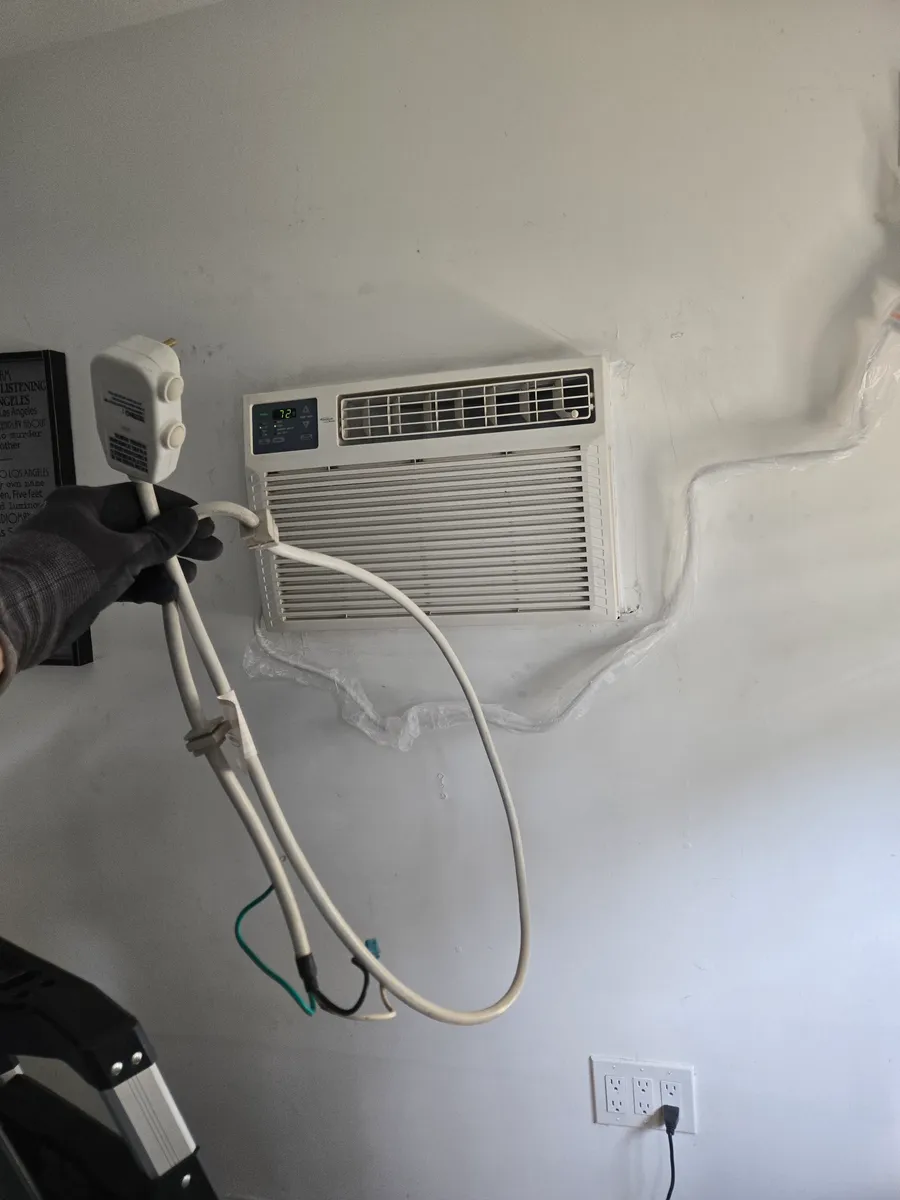 Complete protected power cord assembly beside a window AC